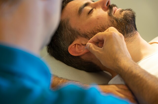 Dr. Hochreiter während einer Ohr-Akupunktur-Behandlung.